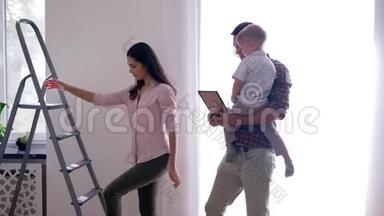 公寓、幸福家庭的装修团队合作，孩子在公寓里做修理，用梯子在公寓里挂画
